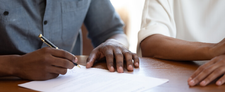 a couples hands singing papers wills trusts and eststae planning